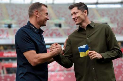 Andriy Shevchenko haciendo entrega a Robert Lewandowski del brazalete con los colores de Ucrania que portará en la Copa del Mundo.